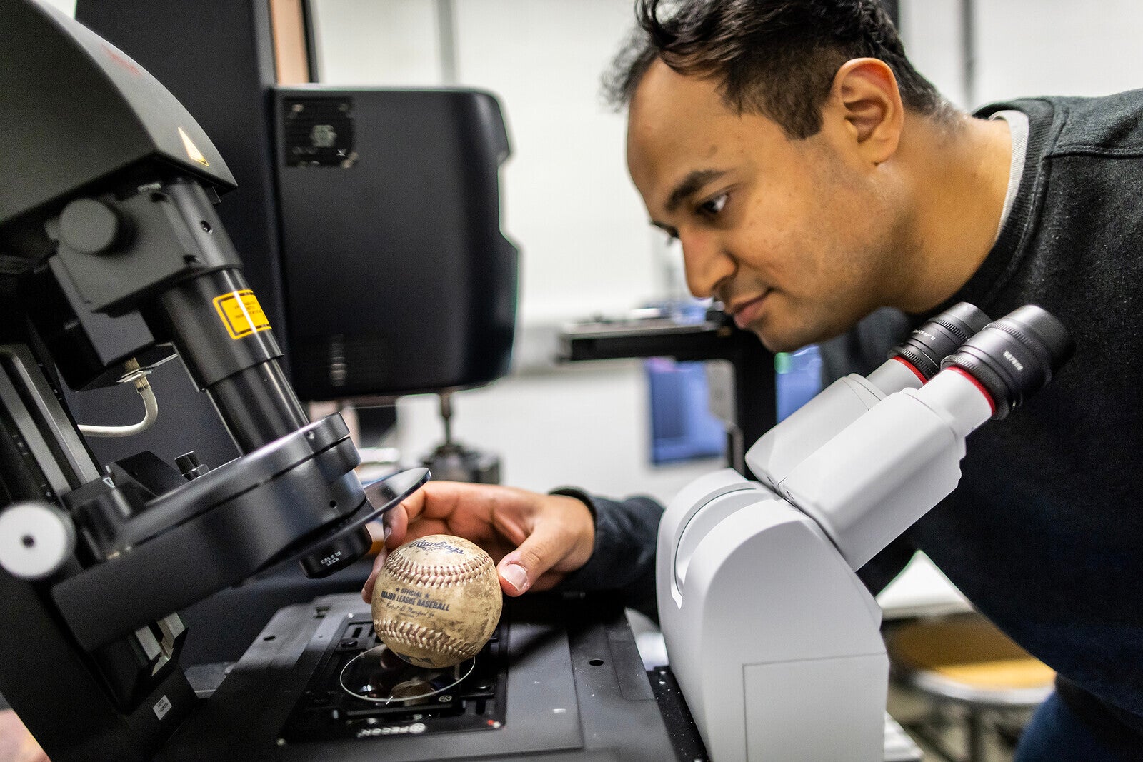 Researcher places muddy baseball under microscope